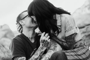 black and white of tattoed couple kissing