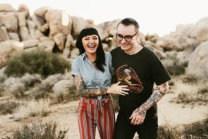 tattooed couple laughing and walking in pinstripe pants joshua tree national park