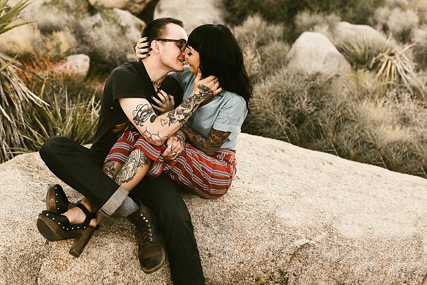tattooed couple sitting and kissing in joshua tree national park