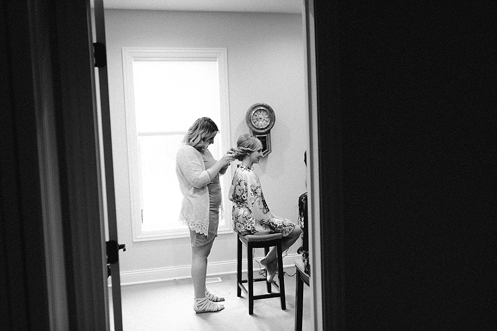 Black and white photo of mother of the bride helping bride get dressed.