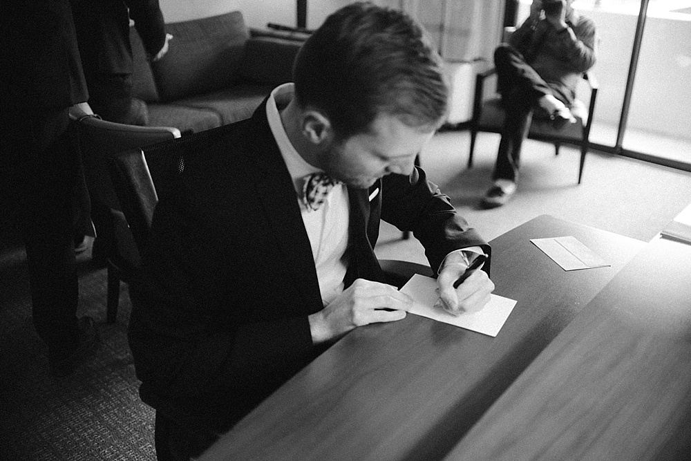 Black and white photo of groom writing his vows.