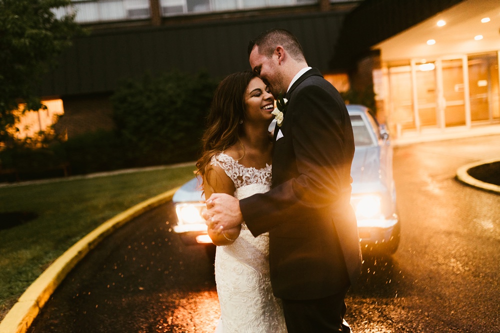 bride and groom dancing in rain in front of vintage car