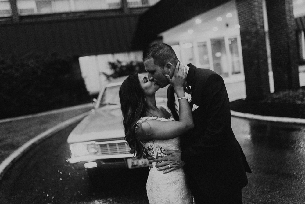 bride and groom kissing in front of vintage car