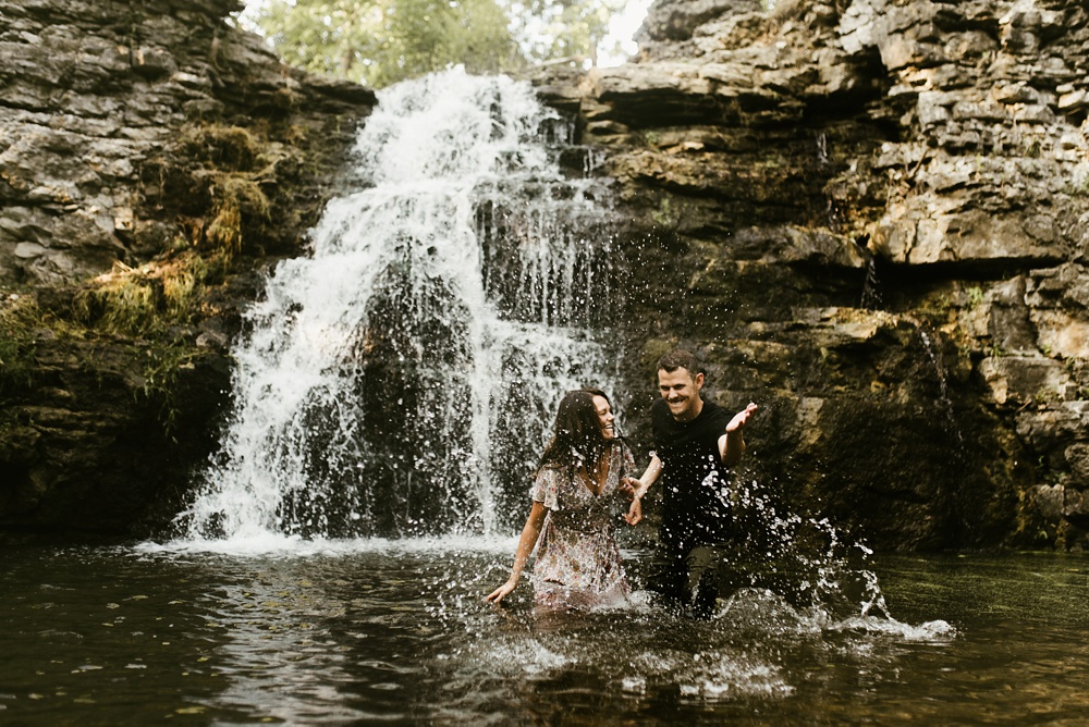 engaged couple splashing in front of france park waterfall