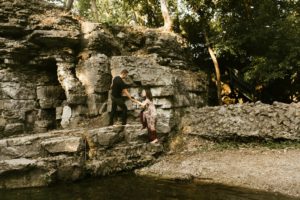 couple climbing up waterfall during engagement session at france park