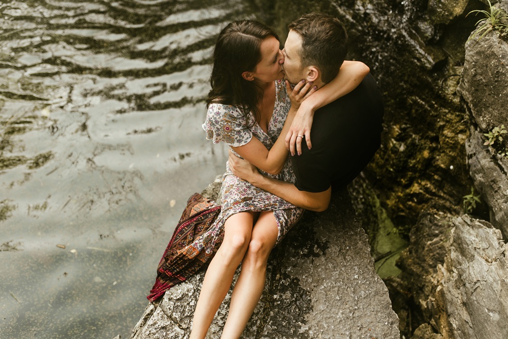 couple kissing next to waterfall during engagement session at france park