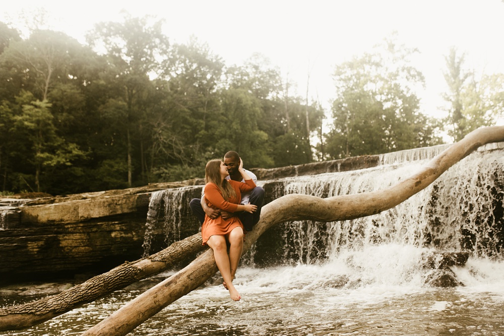 couple on log in front of waterfall at cataract falls