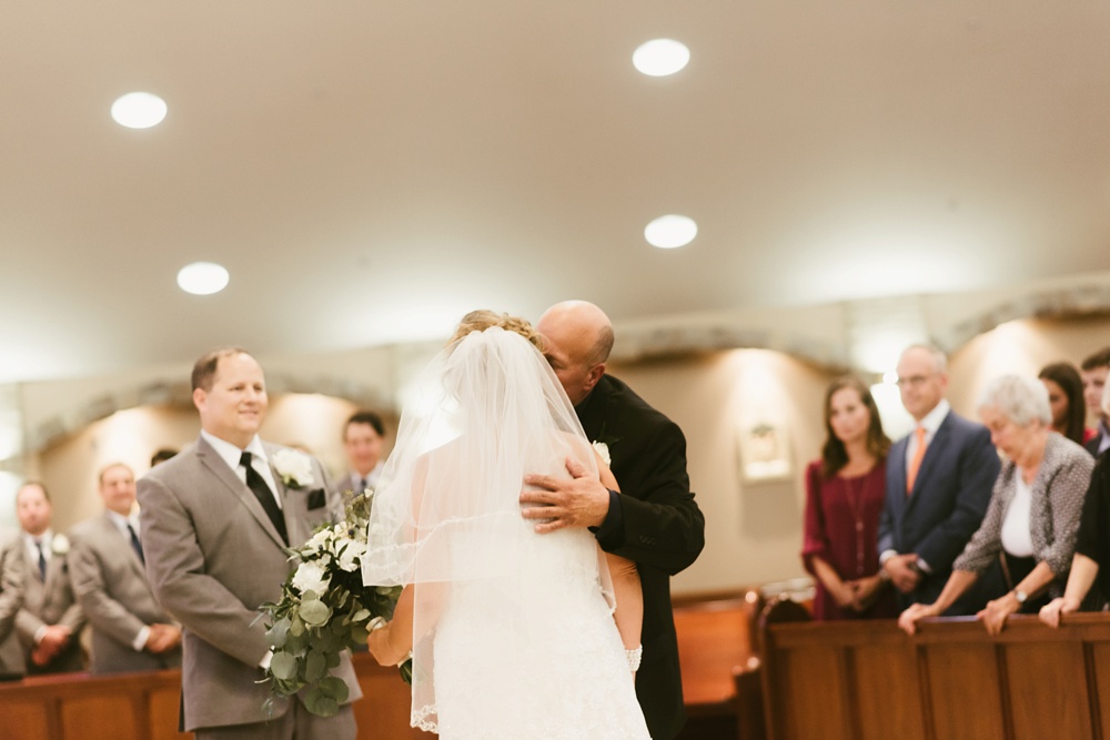 father of bride kissing bride at st. anthony's catholic church
