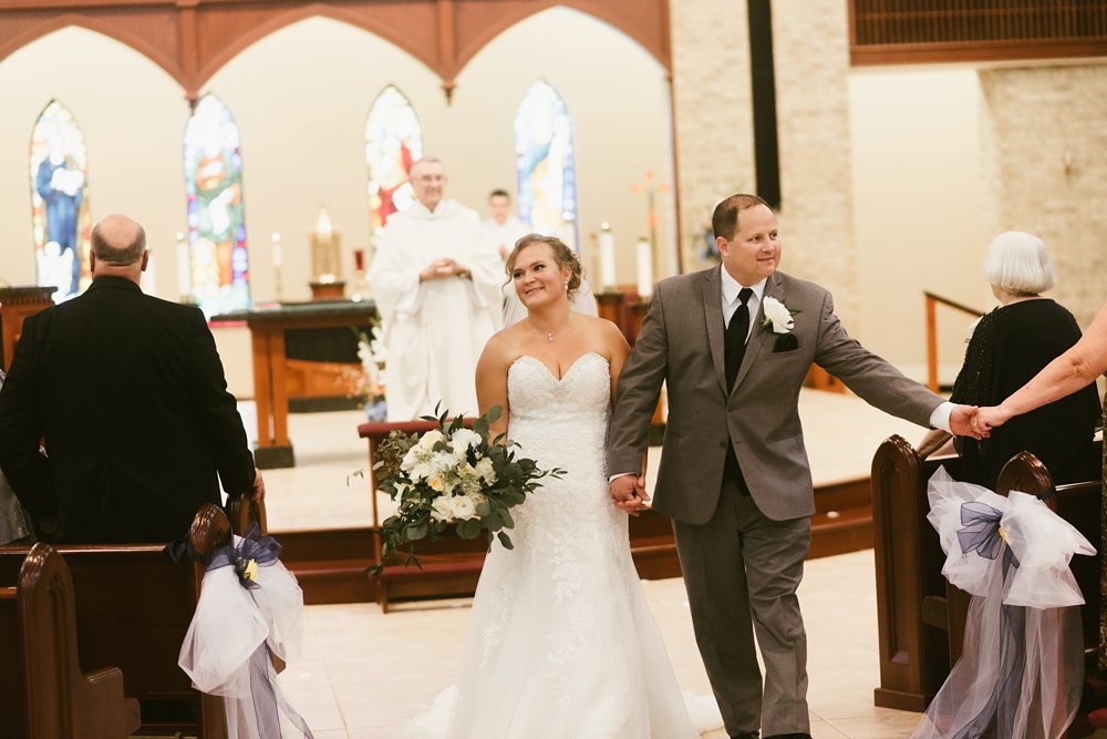 couple walking down aisle during wedding ceremony at st. anthony's catholic church