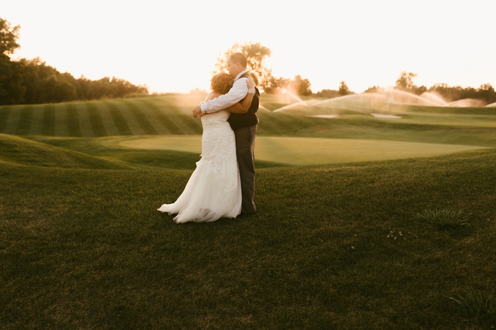 bride and groom hugging in field during sunset at glendarin golf course