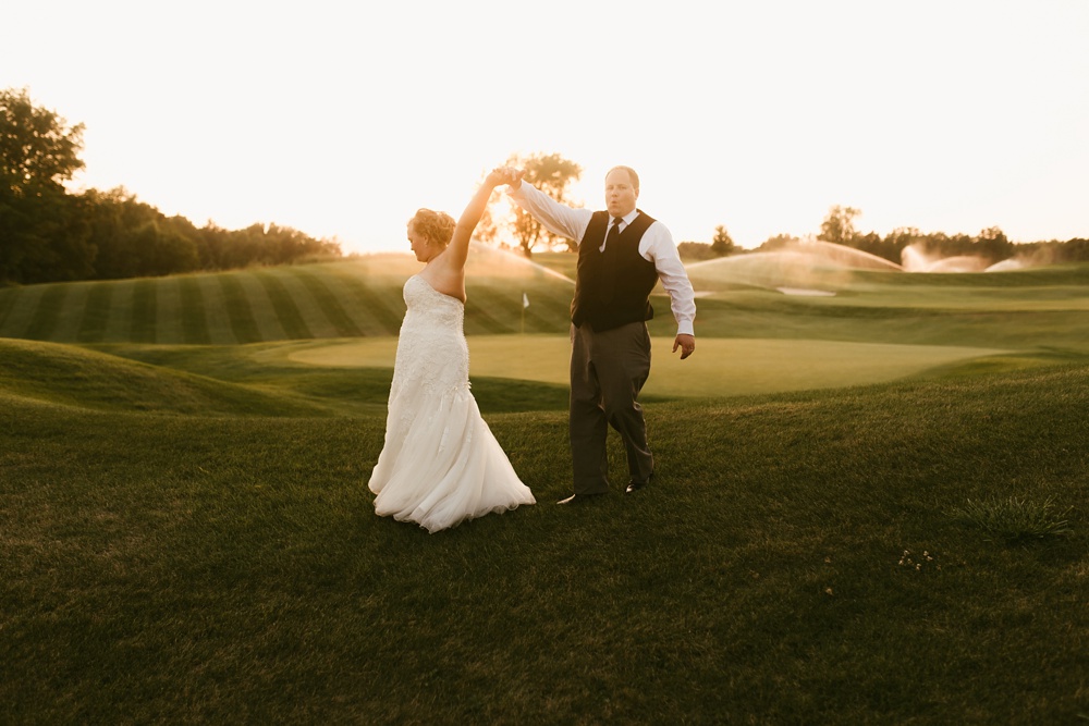 bride and groom dancing in field during sunset at glendarin golf course