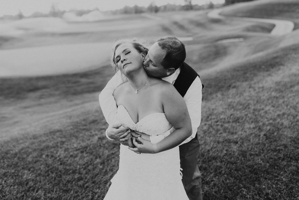 groom kissing bride in field at glendarin golf course