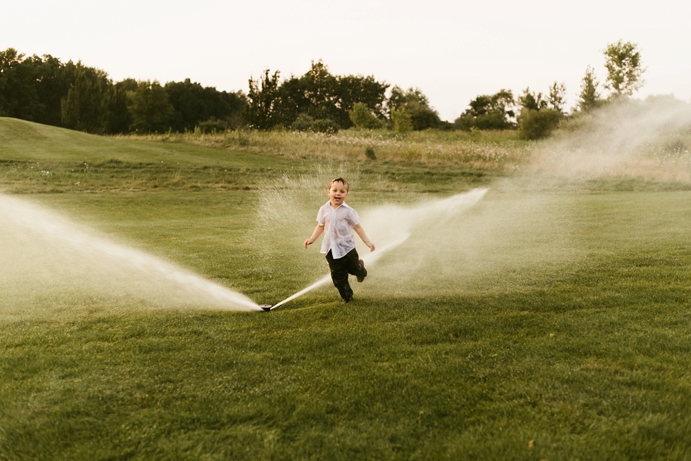 child playing in sprinkler at glendarin golf course wedding