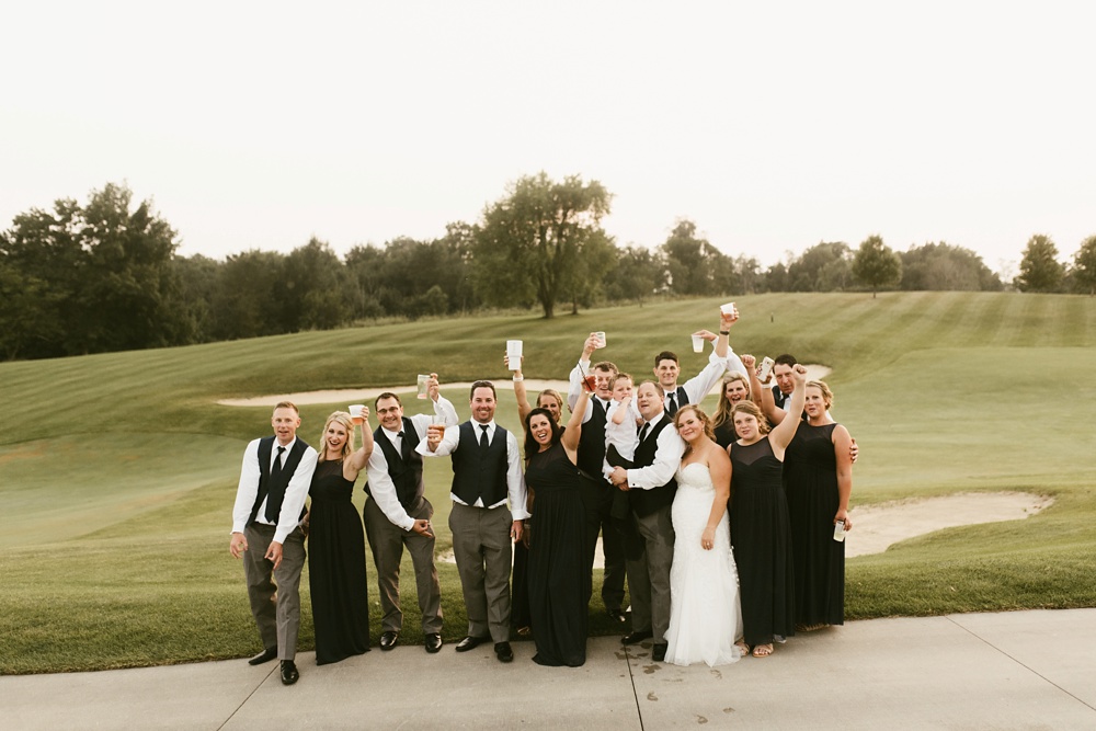 bridal party in navy dresses and gray tuxes cheering at at glendarin golf course sunset