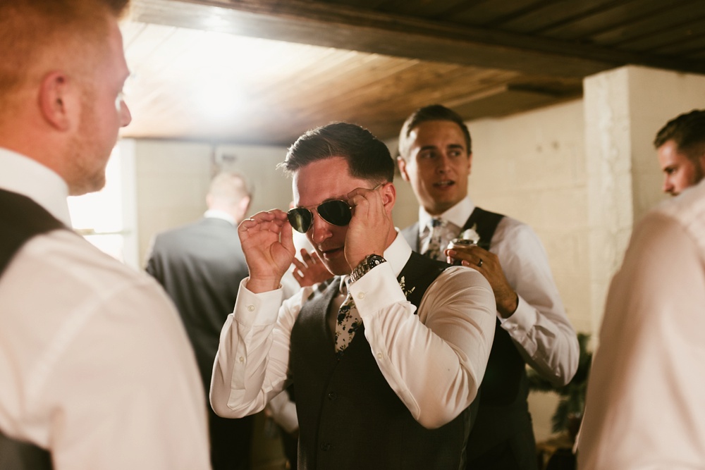 groomsman putting on sunglasses at j weaver barn wedding