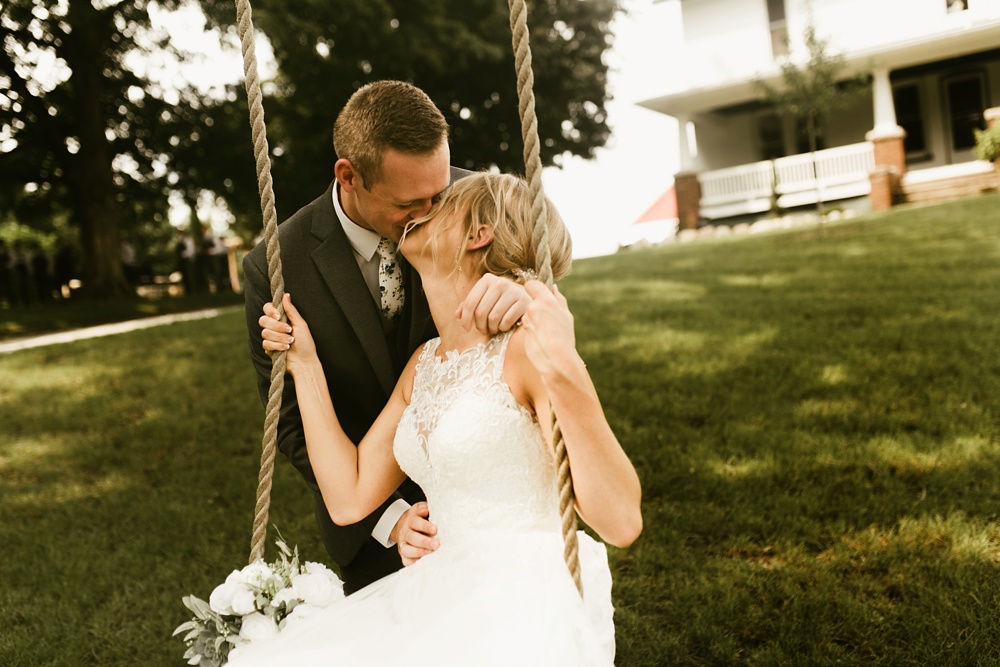 groom kissing bride on swing at j weaver barn wedding