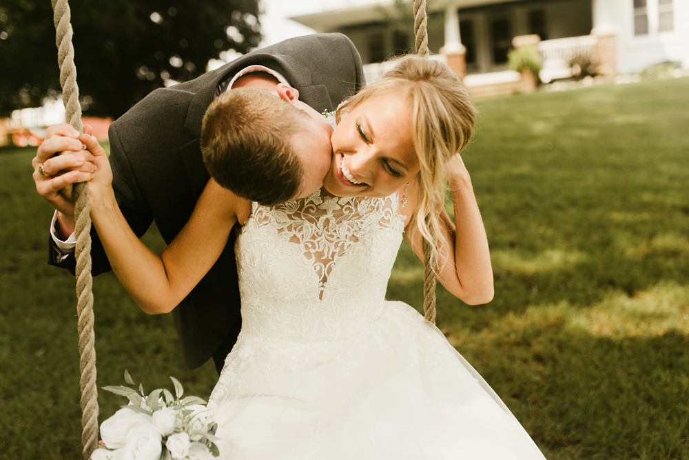 groom kissing bride on swing at j weaver barn wedding