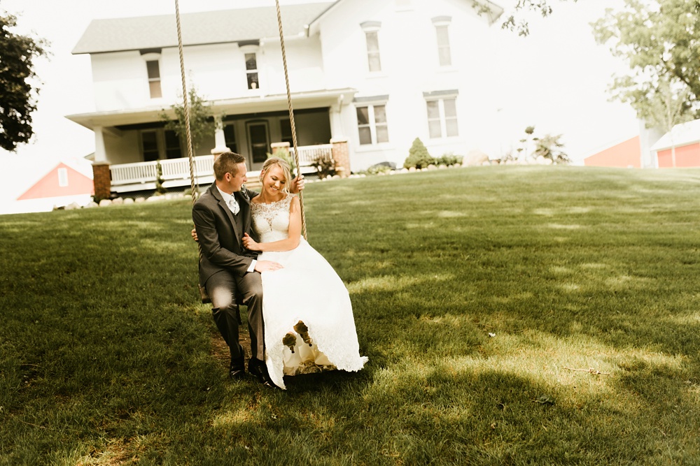 bride and groom sitting on swing at j weaver barn wedding
