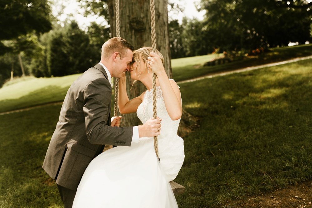 groom and bride smiling on swing at j weaver barn wedding