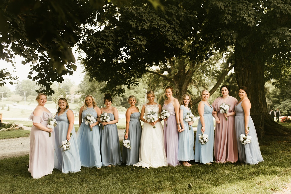 bridal party in pastel dresses with bride at j weaver barn wedding