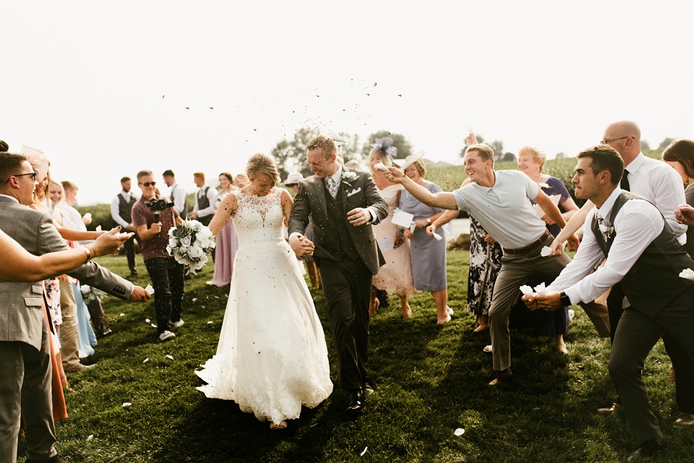 wedding guests throwing confetti at bride and groom at j weaver barn wedding
