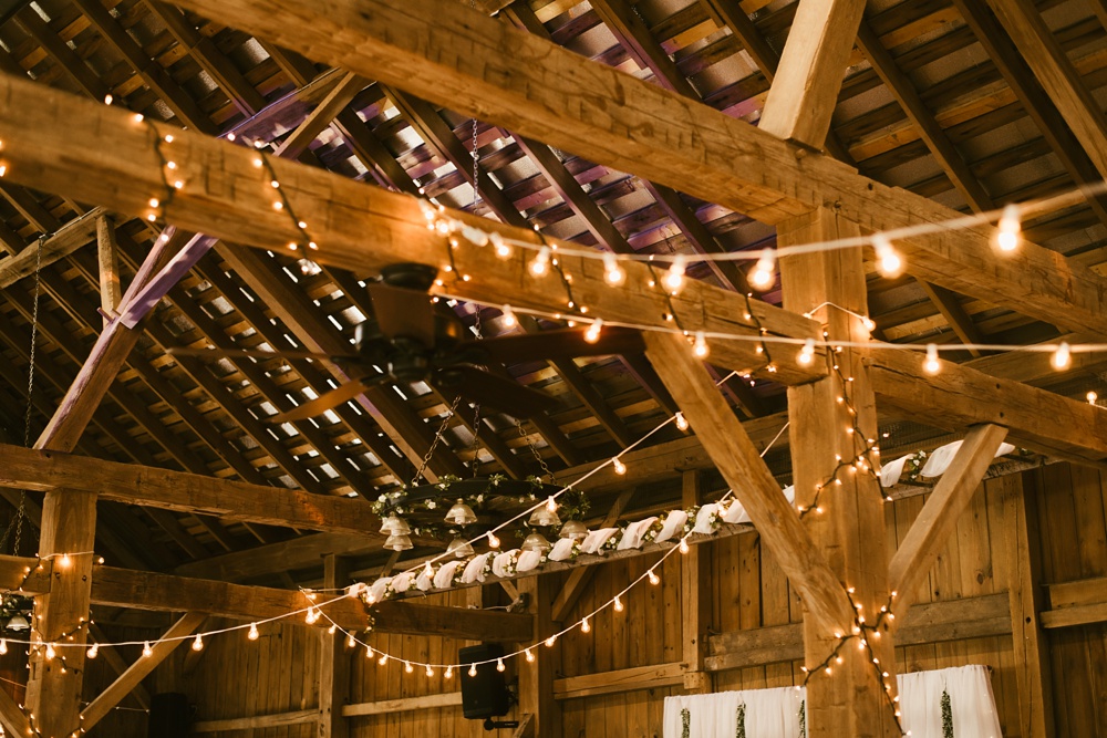market lights on barn rafters at j weaver barn wedding
