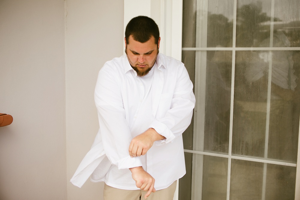 groom buttoning white shirt sleeves at grand palladium jamaica wedding