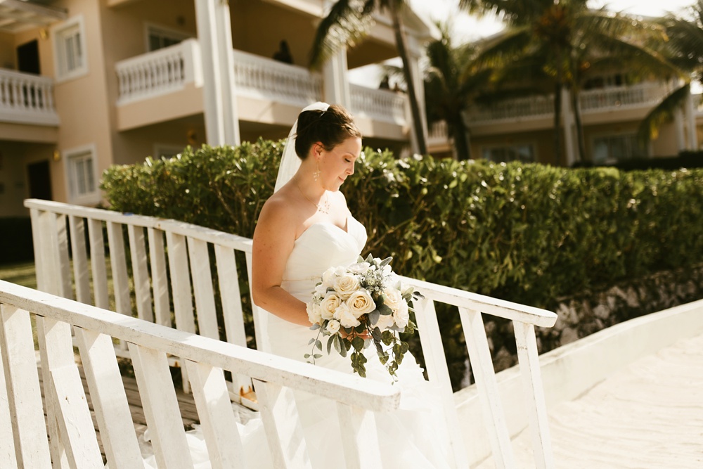 bride walking down stairs to ceremony in davids bridal dress with white rose bouquet at grand palladium jamaica wedding