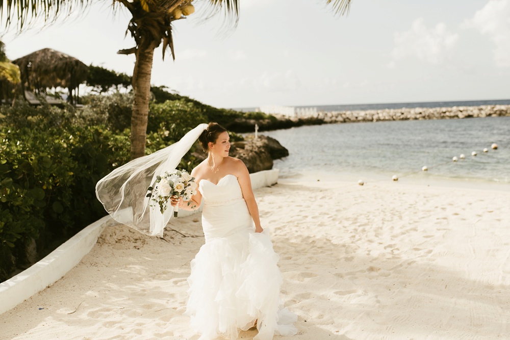bride walking down beach in davids bridal dress and white rose bouquet at grand palladium jamaica wedding