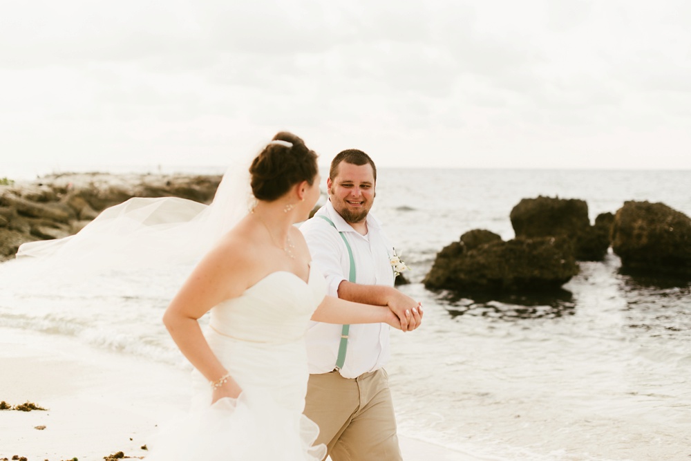 bride and groom holding hands oceanside at grand palladium jamaica wedding