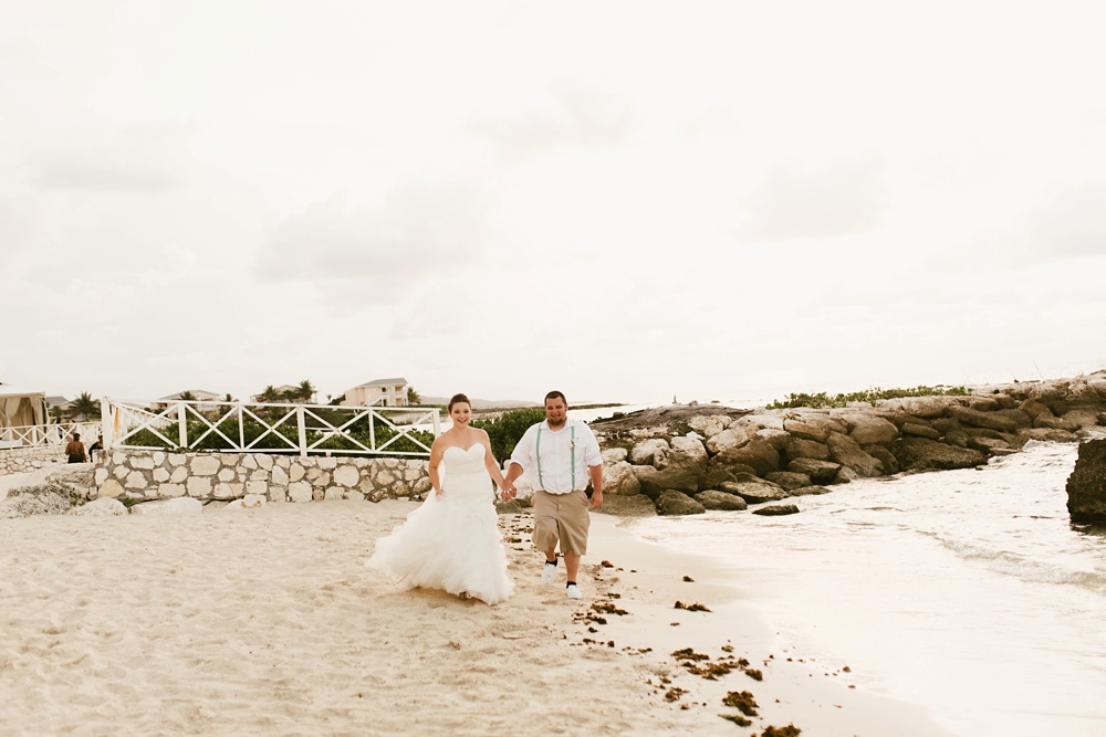 bride and groom holding hands on beach at grand palladium jamaica wedding