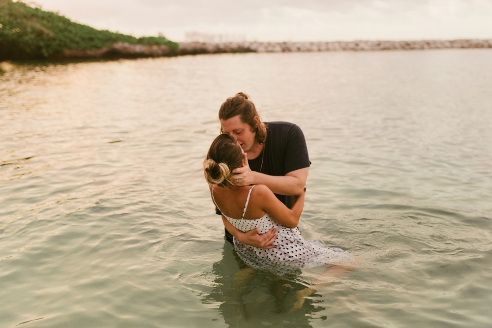 husband kissing wife in ocean water at grand palladium jamaica
