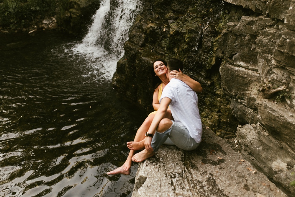 couple hugging and laughing overlooking waterfall at indiana waterfall engagement photoshoot