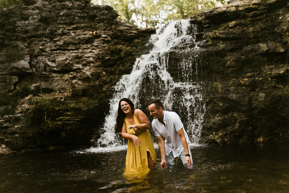couple laughing in water at indiana waterfall engagement photoshoot
