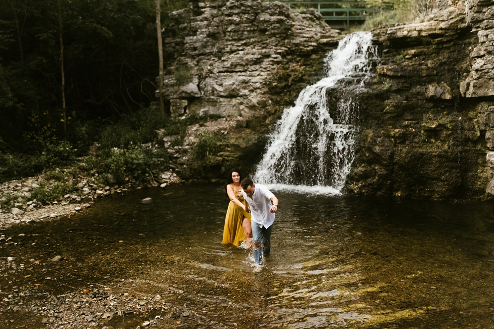 couple holding hands at indiana waterfall engagement photoshoot