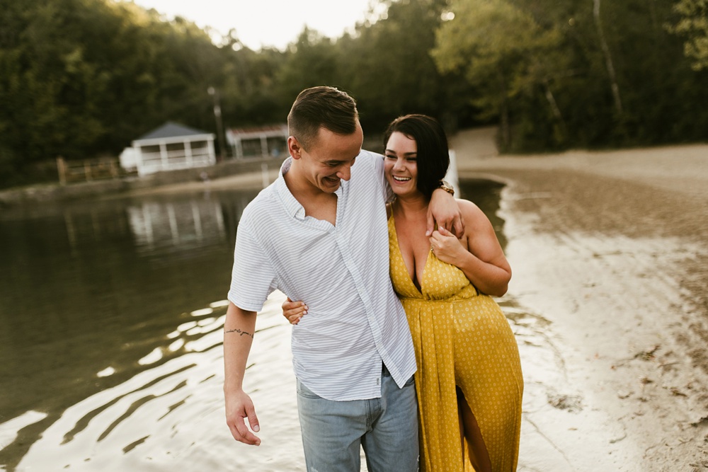 couple hugging and laughing by lake at indiana waterfall engagement photoshoot
