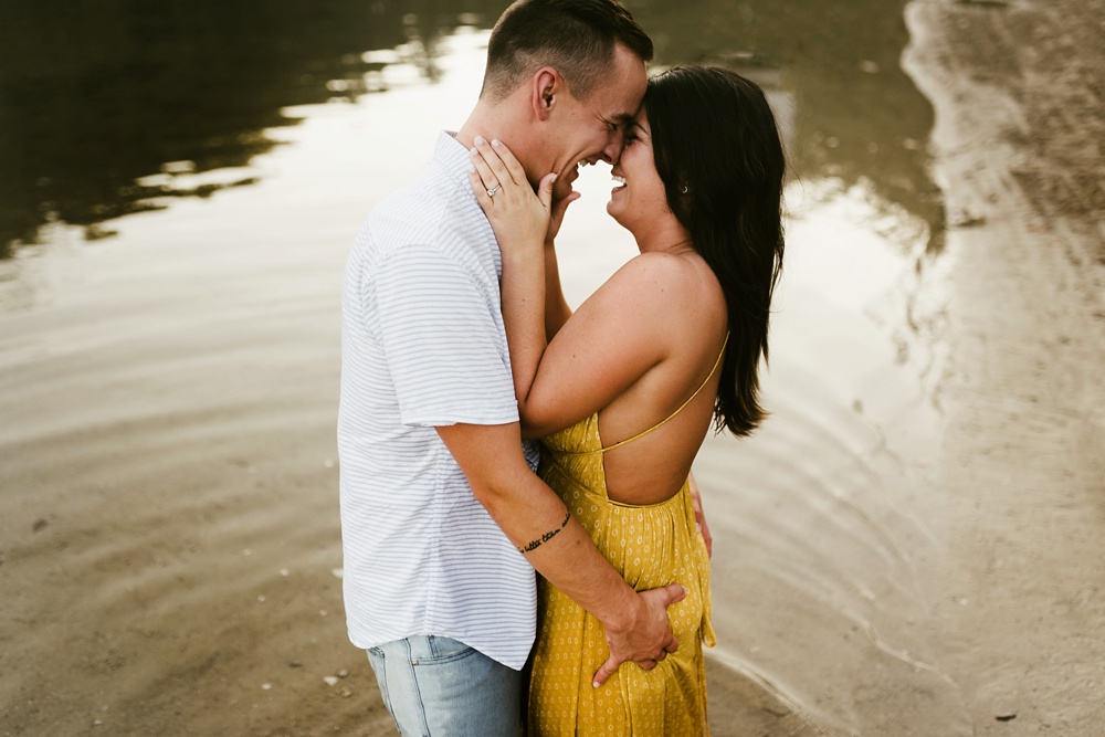 couple hugging and laughing in lake at indiana waterfall engagement photoshoot
