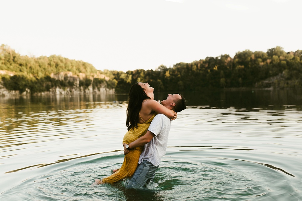 couple hugging and laughing in lake at indiana waterfall engagement photoshoot
