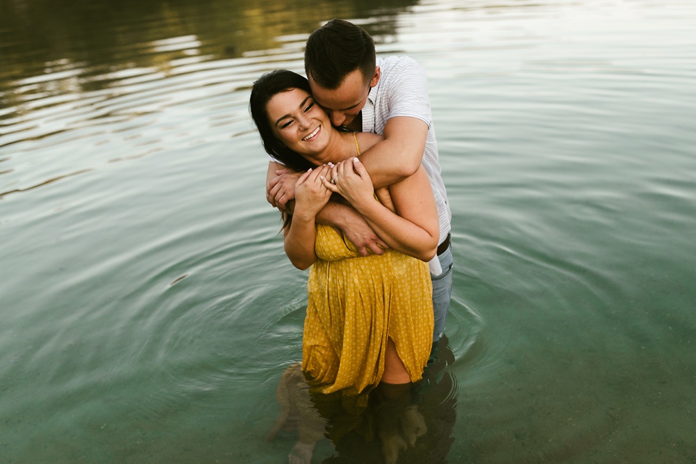couple hugging and smiling in lake at indiana waterfall engagement photoshoot