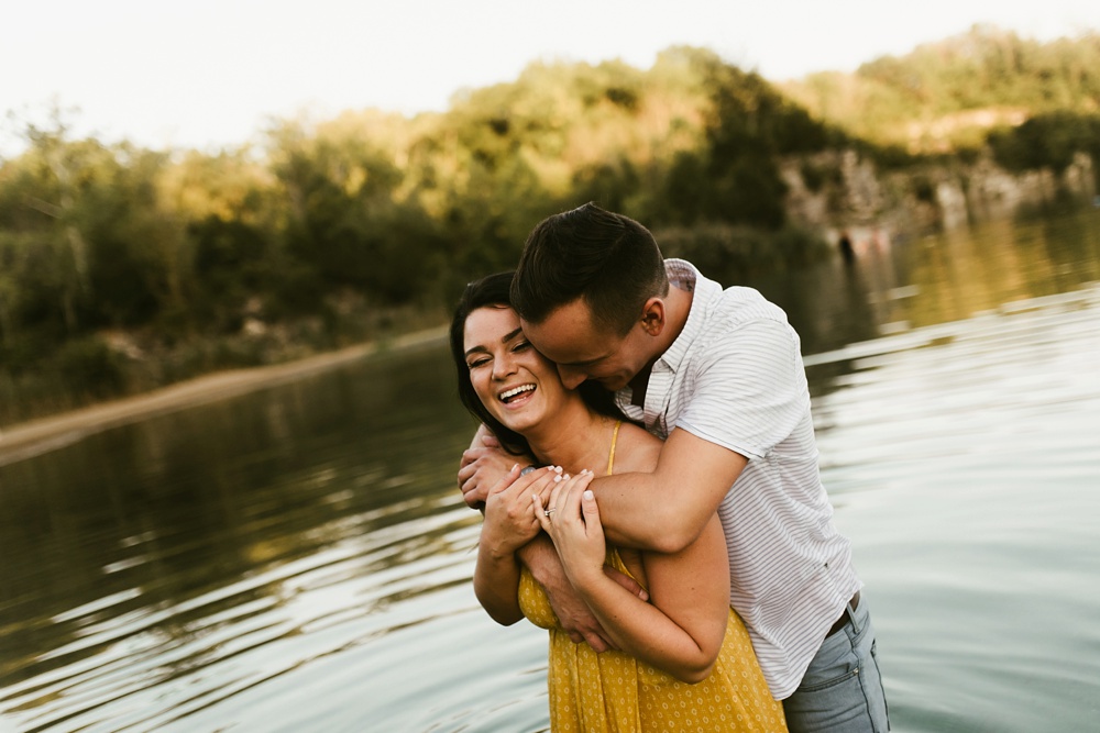 couple smiling and hugging in lake at indiana waterfall engagement photoshoot