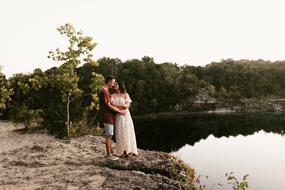 couple hugging on cliff overlooking lake at indiana waterfall engagement photoshoot