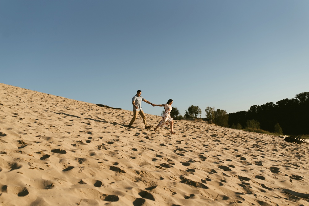 couple walking down dune at dune at warren dunes state park engagement session