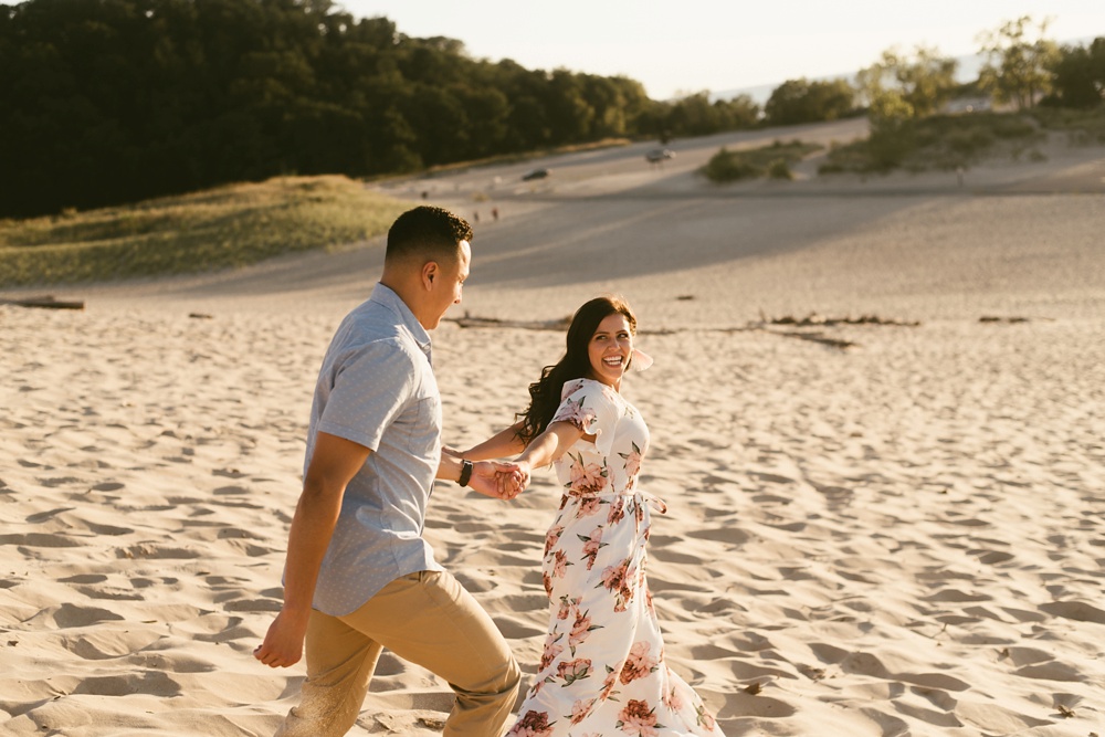 couple holding hands at dune at warren dunes state park engagement session