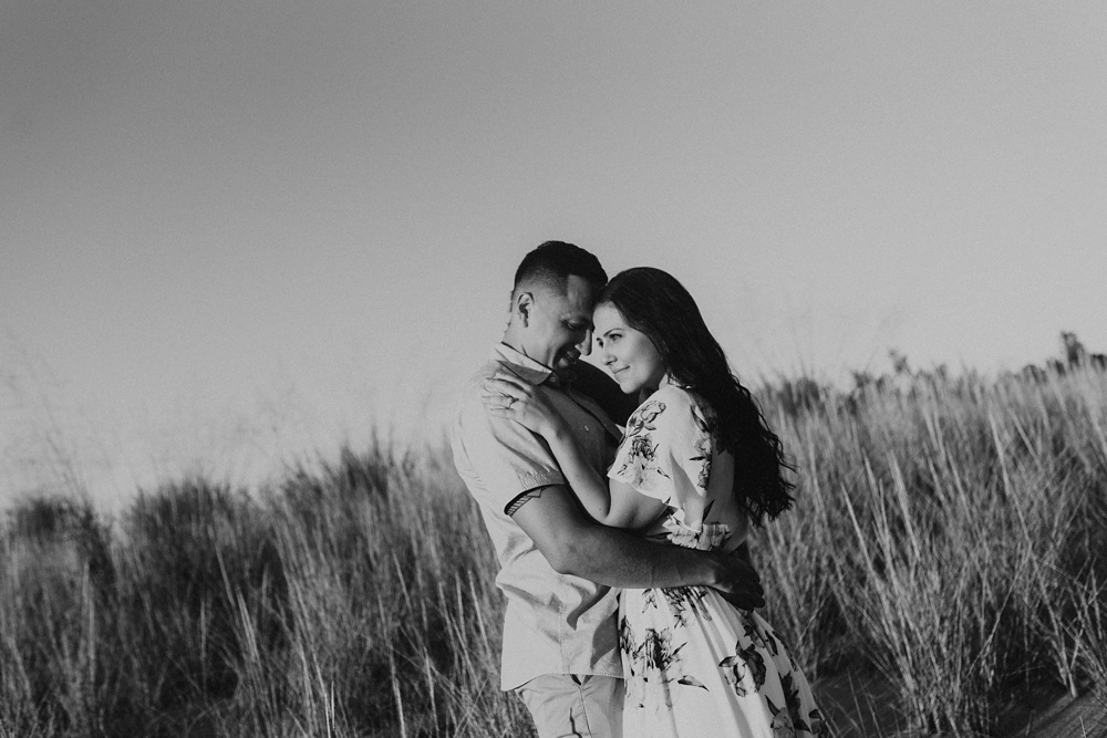 couple hugging in field at dune at warren dunes state park engagement session
