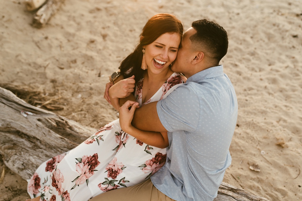 man whispering in fiances ear at dune at warren dunes state park engagement session