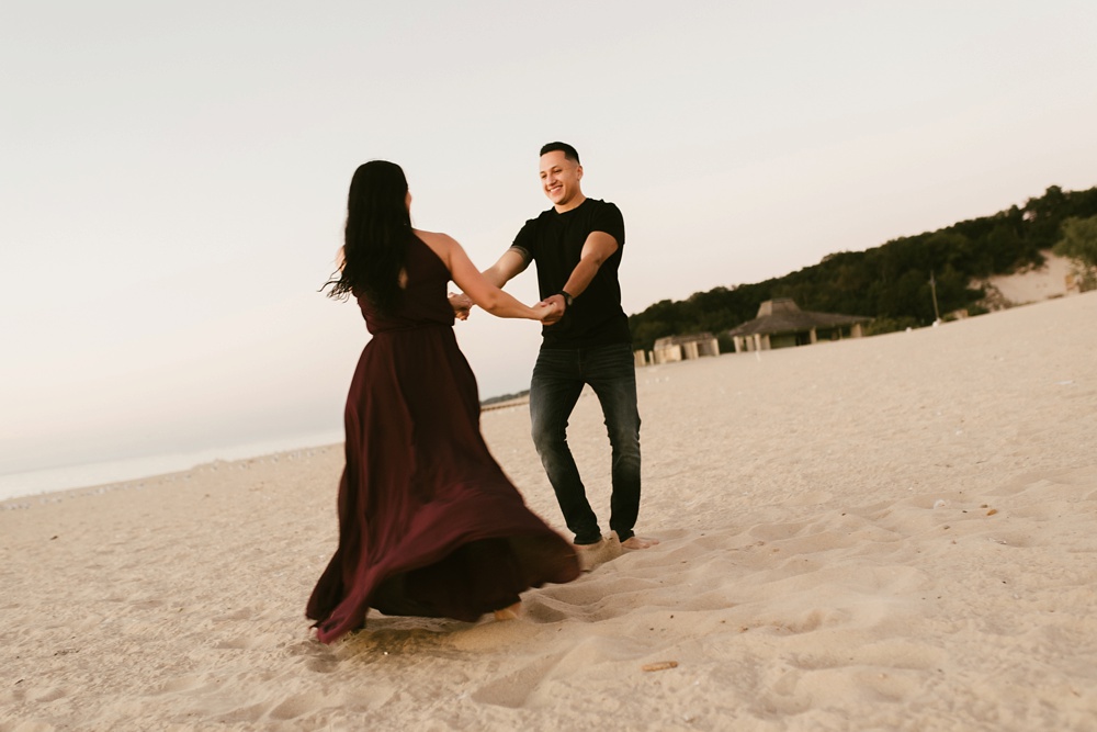 couple holding hands on beac at dune at warren dunes state park engagement session