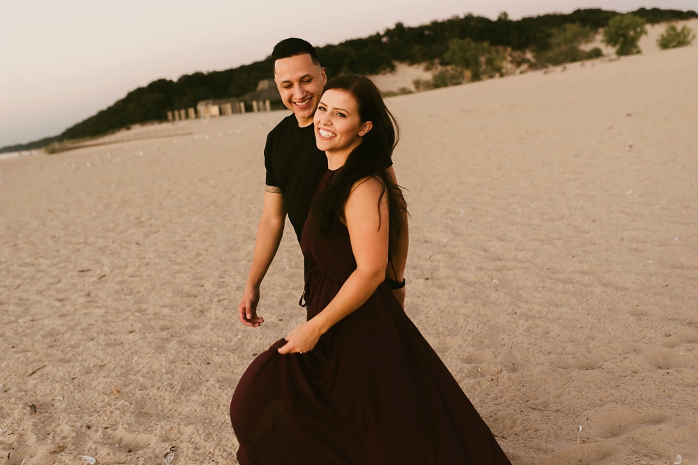 couple laughing on beach at dune at warren dunes state park engagement session