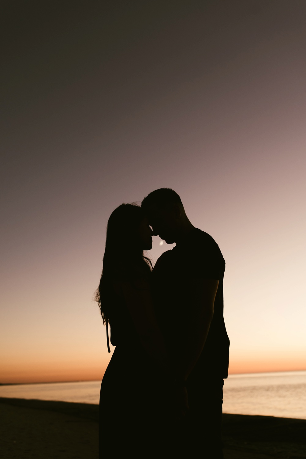 couples silhouette hugging at sunset at dune at warren dunes state park engagement session