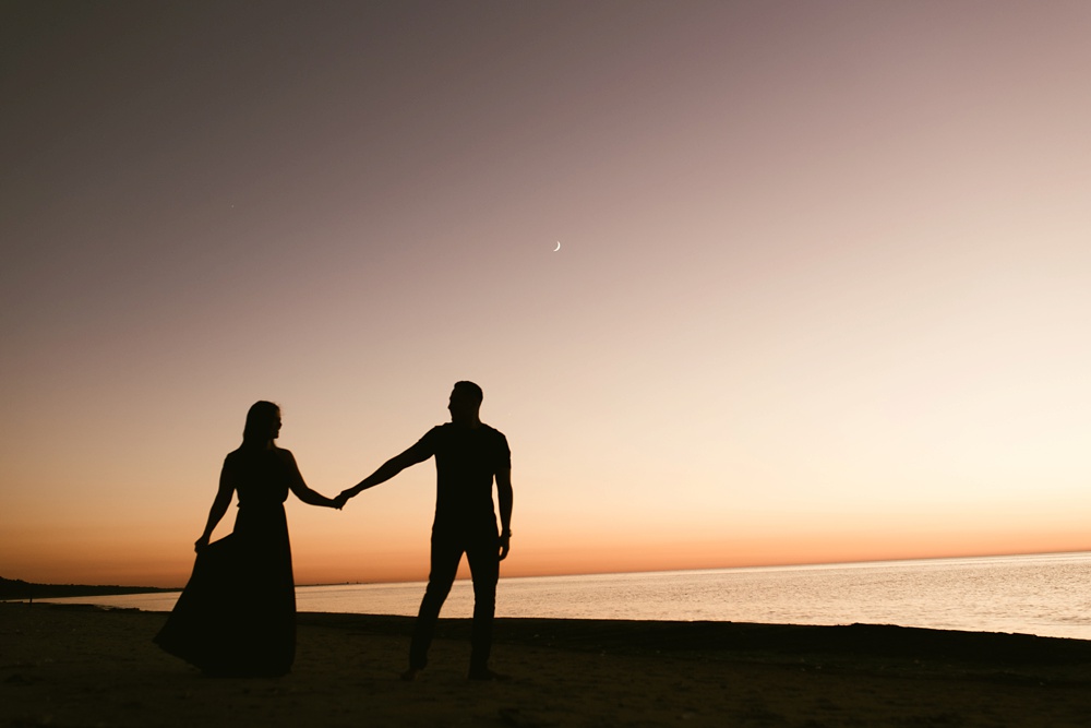 couples silhouettes holding hands at dune at warren dunes state park engagement session