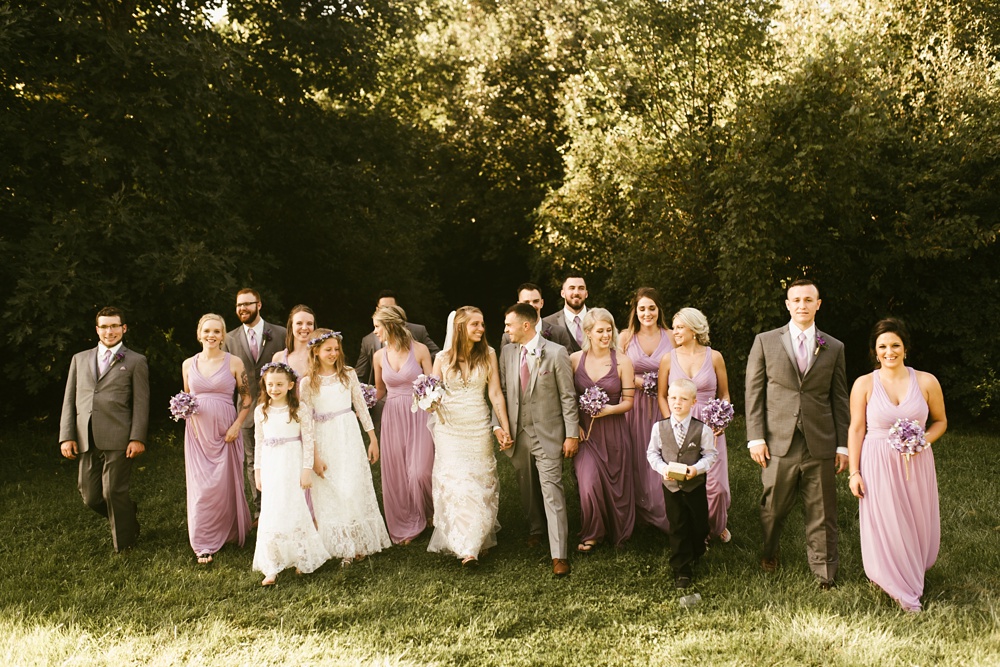 wedding party in lavender dresses and gray tuxes walking with bride and groom at metea county park fall wedding